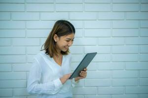 lindo ásia o negócio mulher é em pé lateralmente e olhando às a tábua ela é segurando com uma sorriso, digital marketing. foto