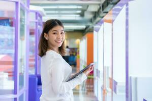 lindo ásia o negócio mulher é em pé com dela costas virou segurando uma tábua, e olhando às a Câmera com uma brilhante sorriso, digital marketing. foto