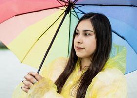 linda mulher morena segurando guarda-chuva colorido na chuva foto