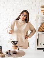 mulher fazendo café na cafeteira, despejando água quente no filtro foto