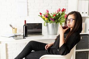 florista de mulher de negócios bebendo vinho, comemorando no escritório foto