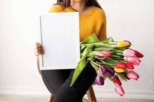 mulher com buquê de tulipas cor de rosa frescas e moldura em branco para simulação de foto