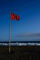 uma vermelho bandeira em a de praia perto a oceano foto