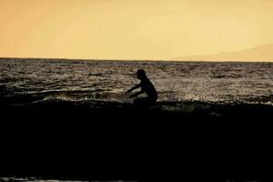 uma surfista passeios uma onda às pôr do sol foto
