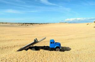 uma azul brinquedo caminhão é sentado dentro a areia foto
