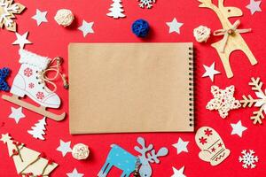 vista superior do notebook, brinquedos de férias e decorações em fundo vermelho de natal. conceito de tempo de ano novo foto