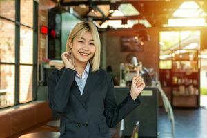 lindo o negócio mulher mostrando dela próprio cafeteria dentro a fundo com orgulhosamente. foto