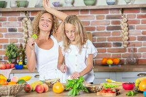 mãe e filhas cozinhando juntos dentro a cozinha. saudável Comida conceito. retrato do feliz família com fresco batidos. feliz irmãs. foto