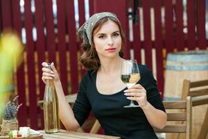 lindo jovem mulher bebendo branco vinho em a terraço do uma restaurante. relaxante depois de trabalhos com uma vidro do vinho. solteiro mulher tendo Diversão. foto