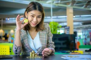 lindo ásia o negócio mulher segurando uma dourado moeda dentro 1 mão foto