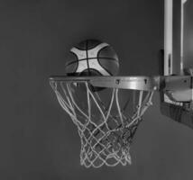 basquetebol bola queda para dentro a cesta em uma Preto fundo foto