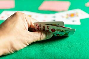 closeup, a mão do homem segurando cartas no jogo de rummy, também chamado de jogo de cartas. fundo desfocado foto