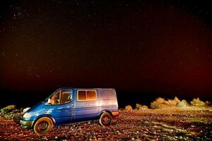 uma azul furgão estacionado debaixo uma estrelado céu foto