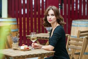 lindo jovem mulher bebendo branco vinho em a terraço do uma restaurante. relaxante depois de trabalhos com uma vidro do vinho. solteiro mulher tendo Diversão. foto