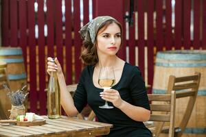 lindo jovem mulher bebendo branco vinho em a terraço do uma restaurante. relaxante depois de trabalhos com uma vidro do vinho. solteiro mulher tendo Diversão. foto