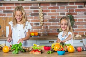 dois pequeno meninas dentro a cozinha com fresco legumes. saudável Comida conceito.. feliz irmãs foto