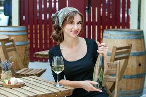 lindo jovem mulher bebendo branco vinho em a terraço do uma restaurante. relaxante depois de trabalhos com uma vidro do vinho. solteiro mulher tendo Diversão. foto