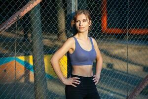 desportivo jovem mulher dentro roupa de esporte fazendo alongamento exercícios ao ar livre. retrato do uma jovem menina fazendo esporte dentro a parque. foto