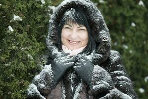 idosos mulher dentro uma pele de capuz coberto com neve foto