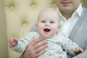 alegre brincalhão bebê dentro dele do pai braços. bebê e Papai foto