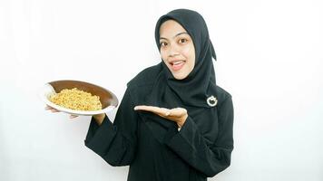 jovem ásia mulher isolado em branco fundo segurando uma prato do Macarrão com garfo e comendo isto foto