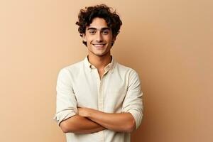 retrato do uma bonito jovem homem com encaracolado cabelo sorridente às Câmera isolado sobre bege fundo, feliz jovem cara. retrato do bonito jovem homem dentro casual camisa guardando braços cruzado, ai gerado foto