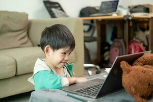 ásia Garoto estudando conectados e fazendo Atividades em computador portátil foto