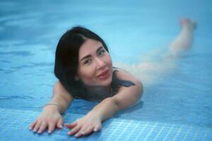 adulto morena relaxamento mentiras dentro geotérmico água dentro piscina às spa recorrer foto
