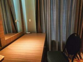 Visão do cadeiras e espelhado mesa dentro hotel quarto foto