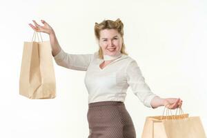 alegre Loiras mulher comprador sorridente e olhando às Câmera, segurando compras papel descartável bolsas foto