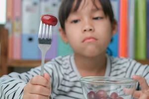 crianças não gostar para comer frutas. fofa jovem ásia menina recusando para comer saudável frutas. nutrição e saudável comendo hábitos para crianças. foto