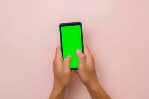 humano mão usando Móvel Smartphone com brincar verde tela em Rosa fundo. masculino mão tocando e pitada para ampliação dentro ou ampliação Fora em em branco digital tela. foto