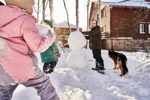 uma família constrói uma boneco de neve Fora do branco neve dentro a Jardim dentro inverno. foto
