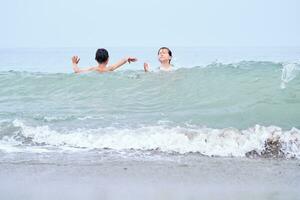 uma Garoto e uma menina estão tendo Diversão jogando dentro a mar dentro a ondas. foto
