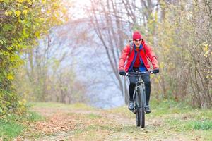 homem esportivo relaxando pedalando uma mountain bike na floresta foto