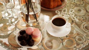 mesa de vidro com uma xícara de café, biscoitos doces. foto