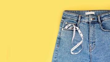 fita métrica e jeans em um fundo amarelo brilhante foto