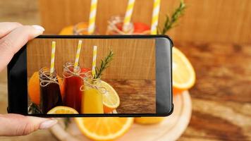 mulher tirando foto de suco de fruta em seu smartphone