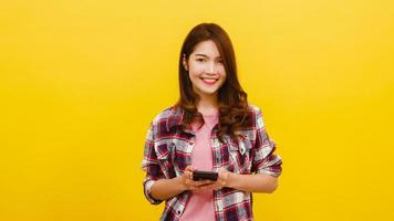 mulher asiática usando telefone com expressão positiva, sorri amplamente. foto