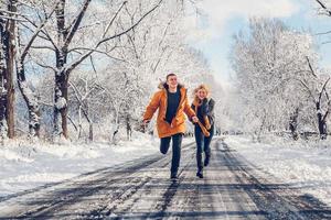 rapaz e moça caminham e se divertem na floresta no inverno foto