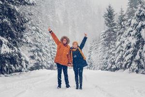 rapaz e moça caminham e se divertem na floresta no inverno foto
