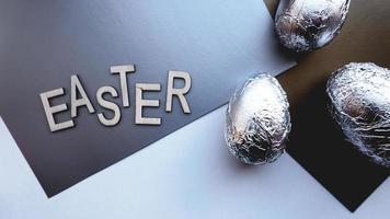 ovos em papel alumínio em fundo prata. conceito de Páscoa. com texto de Páscoa foto