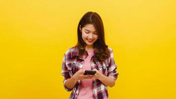 mulher asiática usando telefone com expressão positiva, sorri amplamente. foto