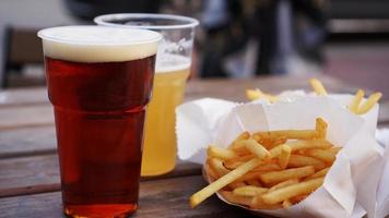 cerveja clara e escura e batatas fritas em uma mesa de madeira foto