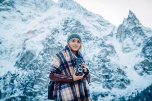 garota com uma câmera velha vintage em um fundo de montanhas de neve foto