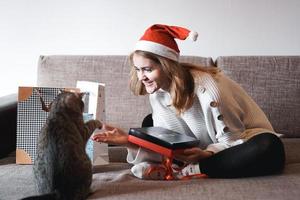 menina feliz com chapéu de Papai Noel abrindo caixa de presente de natal foto