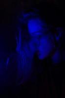 feche o retrato da garota vaping em luz azul neon foto