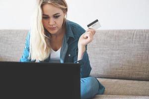 Mulher jovem e bonita trabalhando com laptop e cartão de crédito em casa foto
