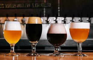 diferente tipos do construir Cerveja dentro óculos em mesa dentro bar interior dentro luz do dia foto