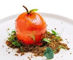 incomum sobremesa dentro a forma do uma tomate em uma branco prato foto